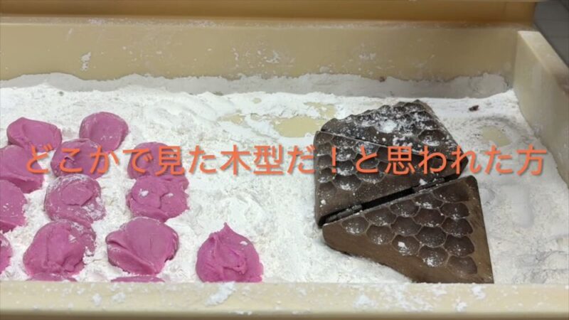 打ち粉をした木箱に並ぶピンクの饅頭生地と、細かな模様が彫られた木型