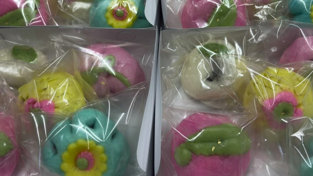 袋詰めされた花まんじゅう。桃、茄子、花などをかたどった色とりどりのお饅頭が箱に並んでいる