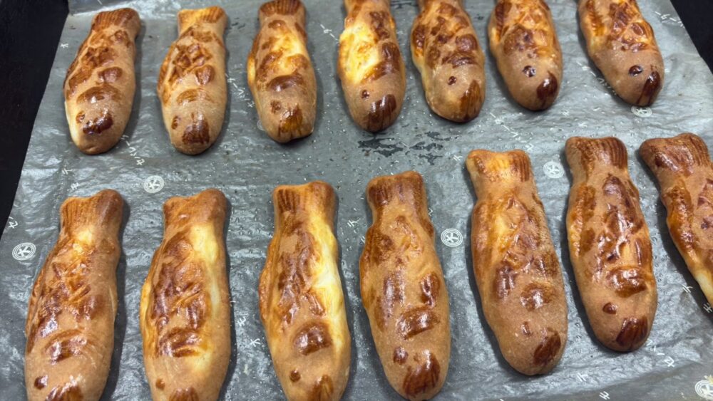 焼き上がったニジマスの形の菓子が鉄板に並ぶ