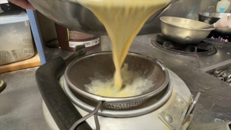 漉し器を通しながら、プリン液を容器に注いでいる